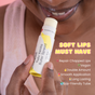 A person applies Yuzu Vanilla Butter Spread lip balm to their lips. Text highlights features: Soft lips must have—repair chapped lips, vegan, double amount, smooth application, long lasting, eco-friendly tube.