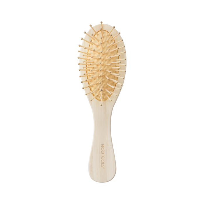 A wooden hairbrush with a light-colored handle and oval-shaped head, featuring wooden bristles and a cushioned base. The word ECOTOOLS is engraved on the handle. The background is plain white.