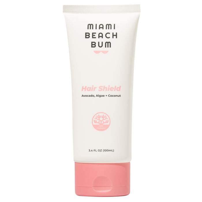 A white tube with a pink cap labeled Miami Beach Bum Hair Shield featuring avocado, algae, and coconut; the tube is 3.4 fl oz (100mL) and includes a pink coral graphic.