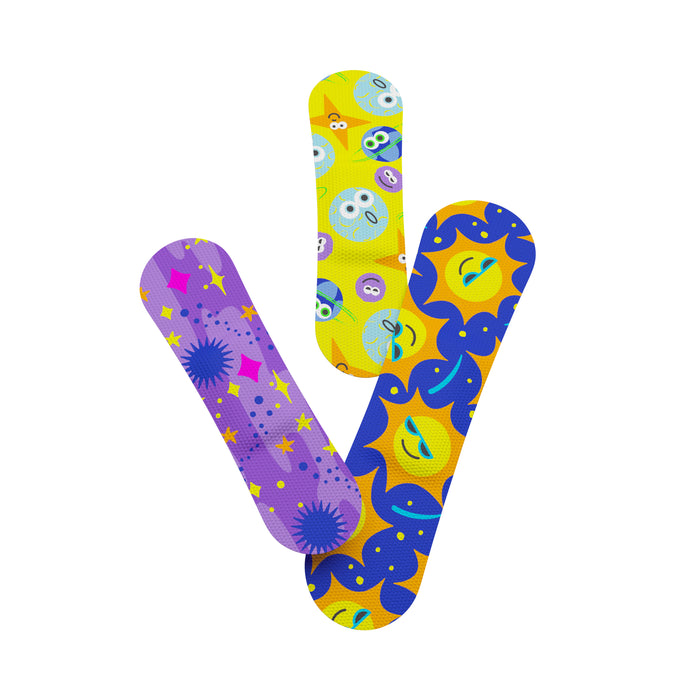 Three colorful adhesive bandages with playful designs: one with purple and pink stars, one yellow with cartoon faces, and one blue and yellow with sun and moon patterns, arranged in a fan shape on a white background.