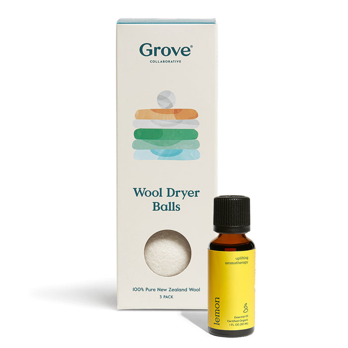 A Wool Dryer Balls + Lemon Essential Oil package from Grove Co. and a small yellow bottle of lemon essential oil with a black cap are side by side. The box boasts all-natural, hypoallergenic dryer balls made from 100% Pure New Zealand Wool, including three wool balls.