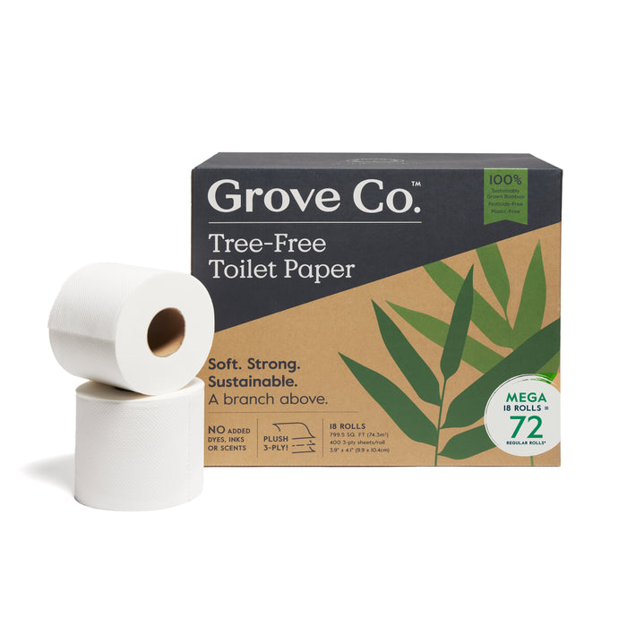 Two white toilet paper rolls are placed in front of a brown and green box labeled “Grove Co. Tree-Free Toilet Paper,” which advertises 18 mega rolls, sustainability, and a leaf design on the packaging.