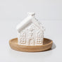 The Plant Therapy Gingerbread House Passive Diffuser, a small white ceramic house on a wooden dish, makes charming holiday décor and gently diffuses your favorite essential oils.