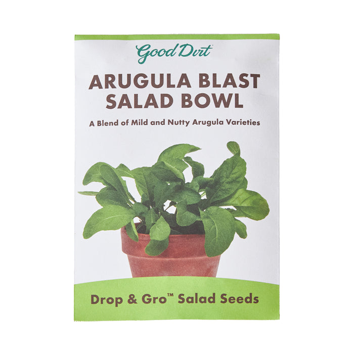 A packet of Good Dirt Arugula Blast Salad Bowl seeds, featuring an image of green arugula leaves in a pot. The packet highlights a blend of mild and nutty arugula varieties and says Drop & Gro Salad Seeds.