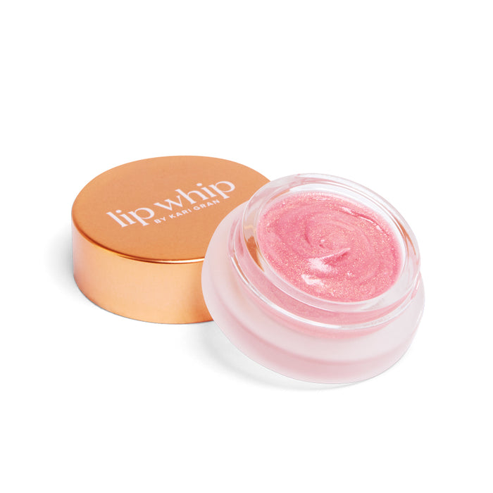 A small round jar of pink shimmery lip balm with a rose gold lid labeled lip whip by Kari Gran, shown with the lid off and placed next to the jar.