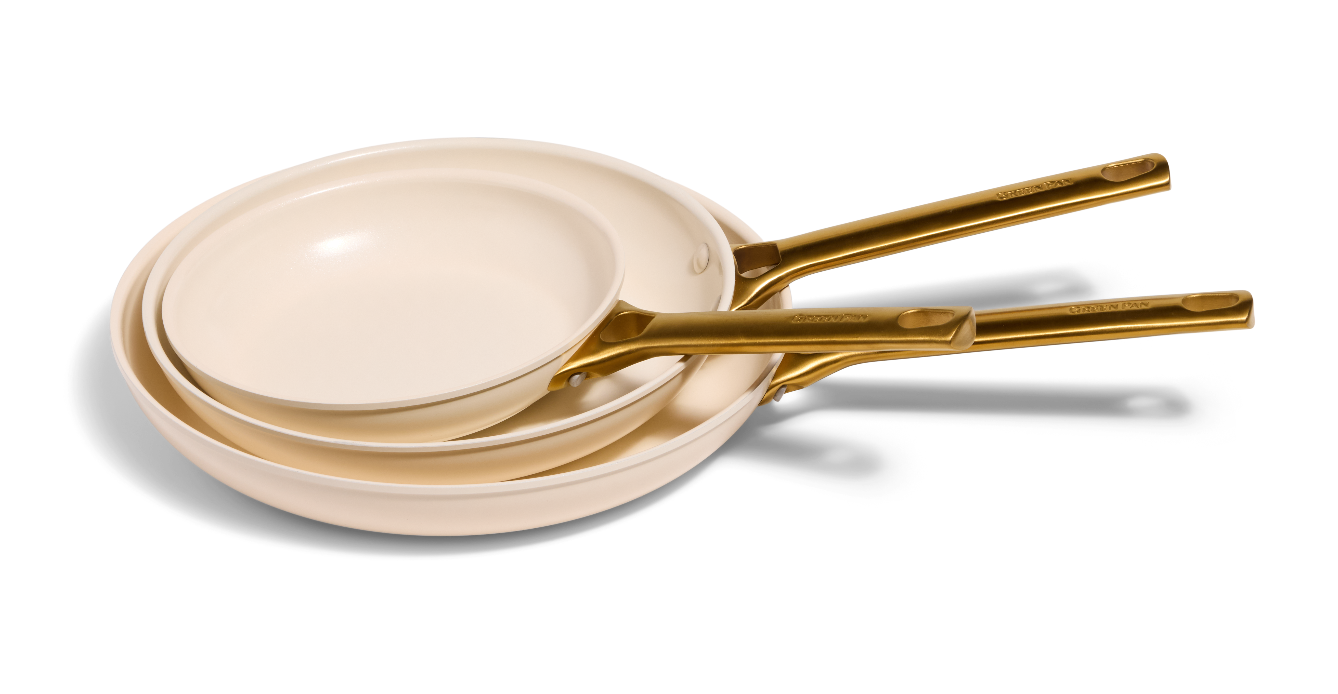 Three cream-colored nonstick frying pans with gold-colored handles, nested together on a light gray background.