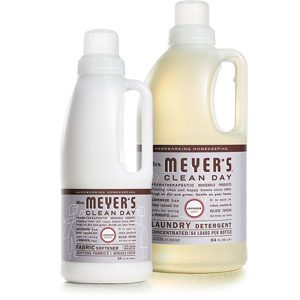 The Mrs. Meyers Laundry Detergent & Fabric Softener Set includes a fabric softener and larger laundry detergent in white with beige labels, featuring a lavender scent. The detergent is behind the soothing Basil Honeysuckle Lavender softener.
