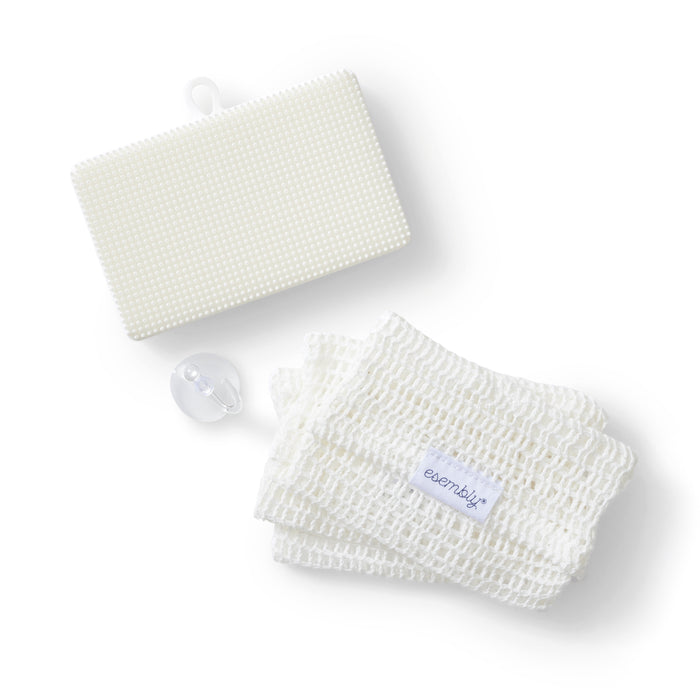 A white textured rectangular sponge, a folded white mesh cloth with a label reading esembly, and a transparent pacifier are arranged on a white background.