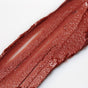 A close-up of a swipe of metallic reddish-brown lipstick with a creamy, shimmery texture on a white surface.
