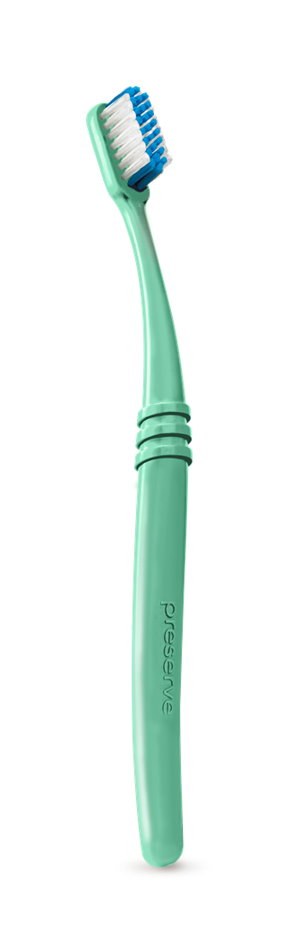 A teal-green toothbrush with blue and white bristles, featuring a curved handle and the word Preserve embossed on it, shown standing upright on a plain light background.