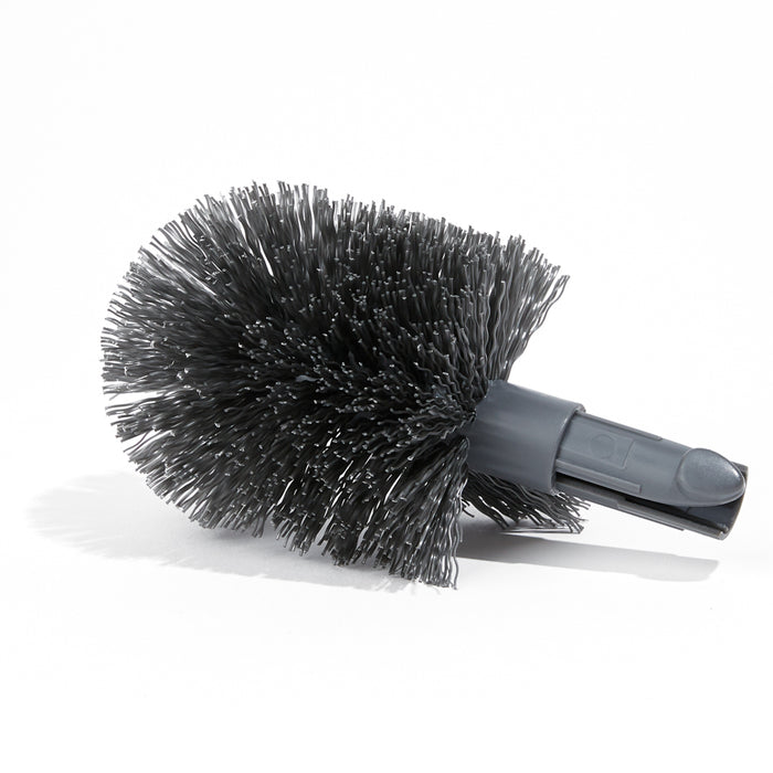 A round, black cleaning brush head with dense, stiff bristles and a plastic attachment handle lying on a white surface.