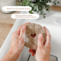 A person washes dishes with Scrub Be Love's Round Heart Dish Sponge (4-Pack), a round, brown coconut coir sponge featuring a heart cut-out. Text bubbles note its quick-drying, antimicrobial, odor-preventing, and plastic-free features.