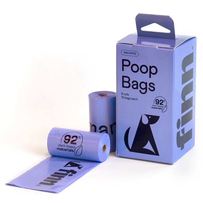 A box with Finn Poop Bags made from 92% USDA Certified Biobased Product sits beside two rolls of purple bags and an open bag. Featuring a playful dog graphic, these eco-friendly poop bags flaunt plant-based materials as sustainable pet products.