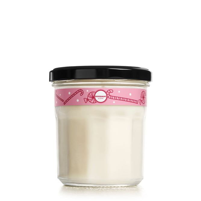 A Mrs. Meyer's Soy Glass Jar Candle, filled with a white vegan candle and sealed with a black lid, sits in a glass jar featuring a pink label adorned with candy cane and peppermint designs against a plain white background.