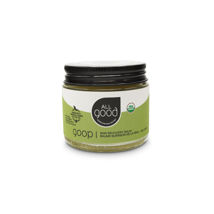 A small glass jar with a black lid, labeled All Good goop Skin Recovery Balm. The label also displays USDA organic and cruelty-free logos. The jar contains a greenish balm.