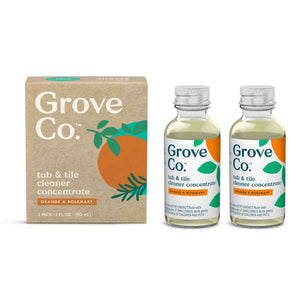 Two bottles of Grove Co. Tub & Tile Cleaner Concentrate with orange and rosemary scent sit next to recyclable packaging. The label has an orange graphic and green leaves, emphasizing the cleaners bio-based ingredients for an eco-friendly touch.