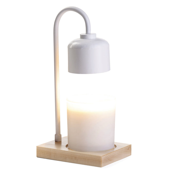 A white lamp with a curved metal arm and dome-shaped shade illuminates a candle in a glass jar, both placed on a square wooden base.