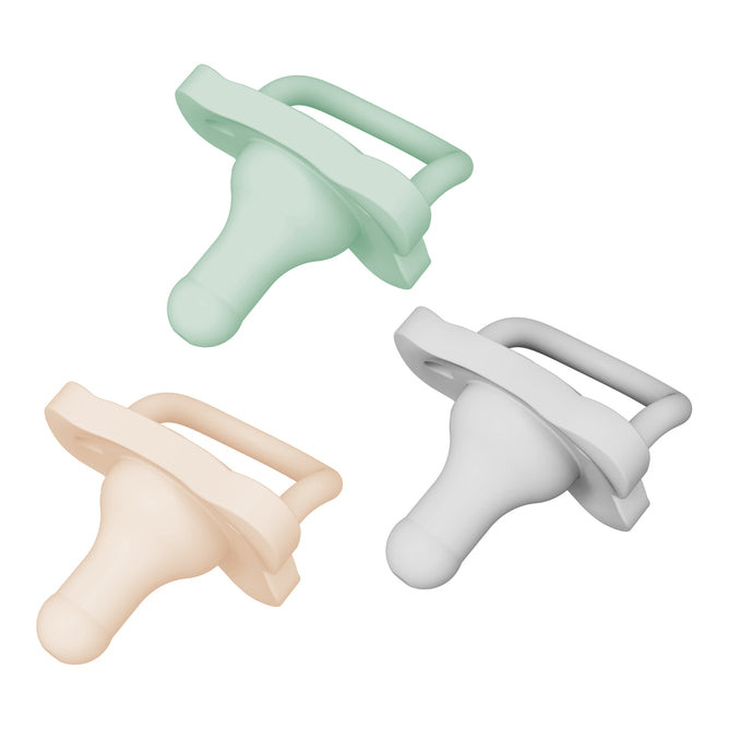 Three silicone baby pacifiers in pastel colors—mint green, light peach, and light gray—are arranged on a white background. Each pacifier has a bulb shape and a handle.
