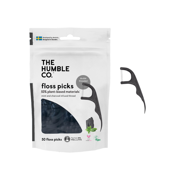 A package of The Humble Co. floss picks, showing one black floss pick beside the bag. The packaging highlights plant-based materials, double threads, and mint and charcoal-infused thread.