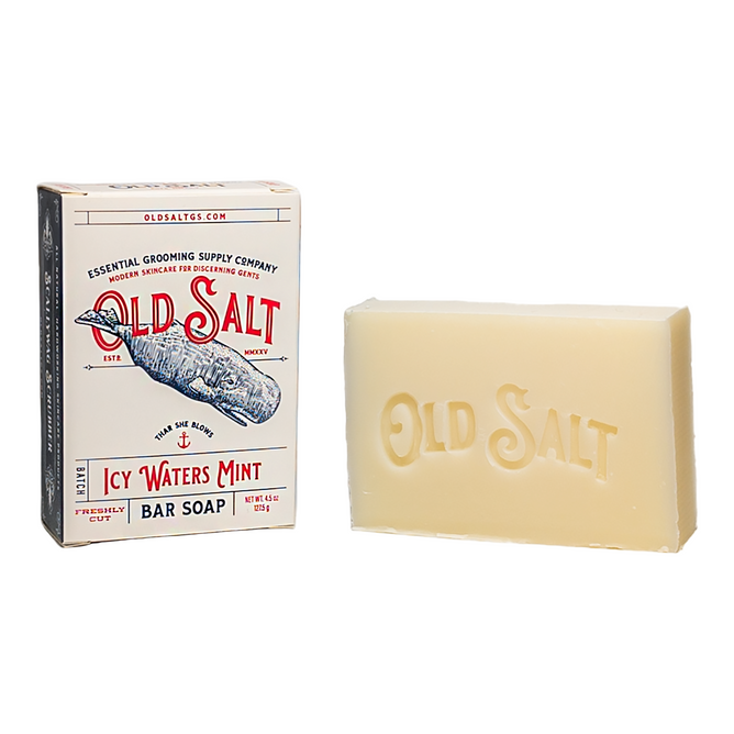 A rectangular Old Salt Bar Soap embossed with "OLD SALT" rests beside its box labeled Old Salt Bar Soap, featuring nautical packaging with a walrus illustration.