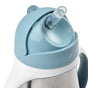 Close-up of a light blue and white sippy cup with a clear plastic straw extending from the lid. The design features a rounded top and a handle, suggesting its intended for young children.