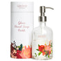 A clear glass hand soap bottle with a metal pump dispenser and colorful floral design, placed next to its matching white cylindrical packaging labeled GROVE collaborative Glass Hand Soap Bottle.