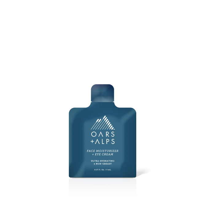 The Oars + Alps Face & Eye Cream - Sample is a 5 mL, non-greasy, ultra-hydrating sachet enriched with Jojoba Oil. It features white text and the brands mountain logo on a small, dark blue package.