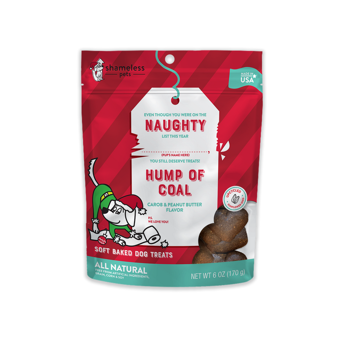 A red bag of Shameless Pets Hump of Coal soft baked dog treats, carob and peanut butter flavor. The bag features a cartoon dog in a Santa hat and scarf, with Naughty List text and visible treat shapes. Net weight is 6 oz.
