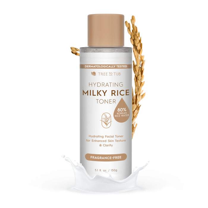 A bottle of Tree to Tub Hydrating Milky Rice Toner with rice stalks beside it and a splash of milky liquid at the base. The label highlights 80% brown rice water and notes that it is fragrance-free.