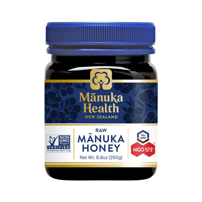 A jar of Manuka Health New Zealand raw Manuka honey, 8.8 oz (250g), featuring a blue lid and label with gold accents, non-GMO project verified, and MGO 573+ rating indicated on the front.