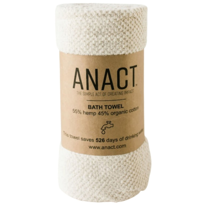 A rolled cream-colored bath towel with a brown label that reads ANACT Bath Towel, 55% hemp 45% organic cotton and notes the towel saves 526 days of drinking water.