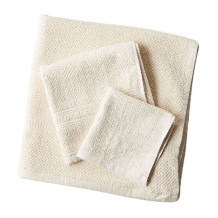 Three neatly folded cream-colored towels of varying sizes are stacked together on a white background.