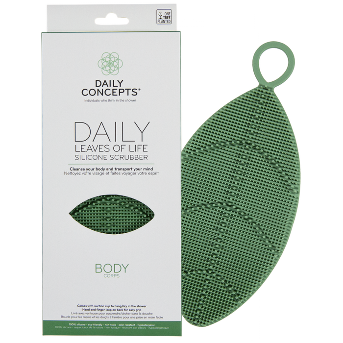 A green, leaf-shaped silicone scrubber with a loop is next to its packaging, which reads DAILY CONCEPTS DAILY LEAVES OF LIFE SILICONE SCRUBBER BODY. The scrubber has small bristles and the box is white with green accents.