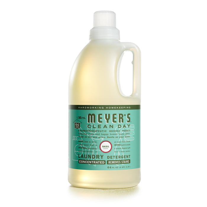 A bottle of Mrs. Meyer’s Clean Day laundry detergent, basil scent, with a light green label and a clear liquid inside. The bottle has a handle and a white cap.