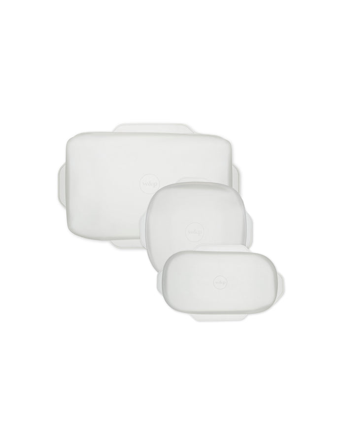Three white, rectangular silicone food storage lids of varying sizes are arranged on a white background, each with small handles on the sides and a subtle circular logo in the center.
