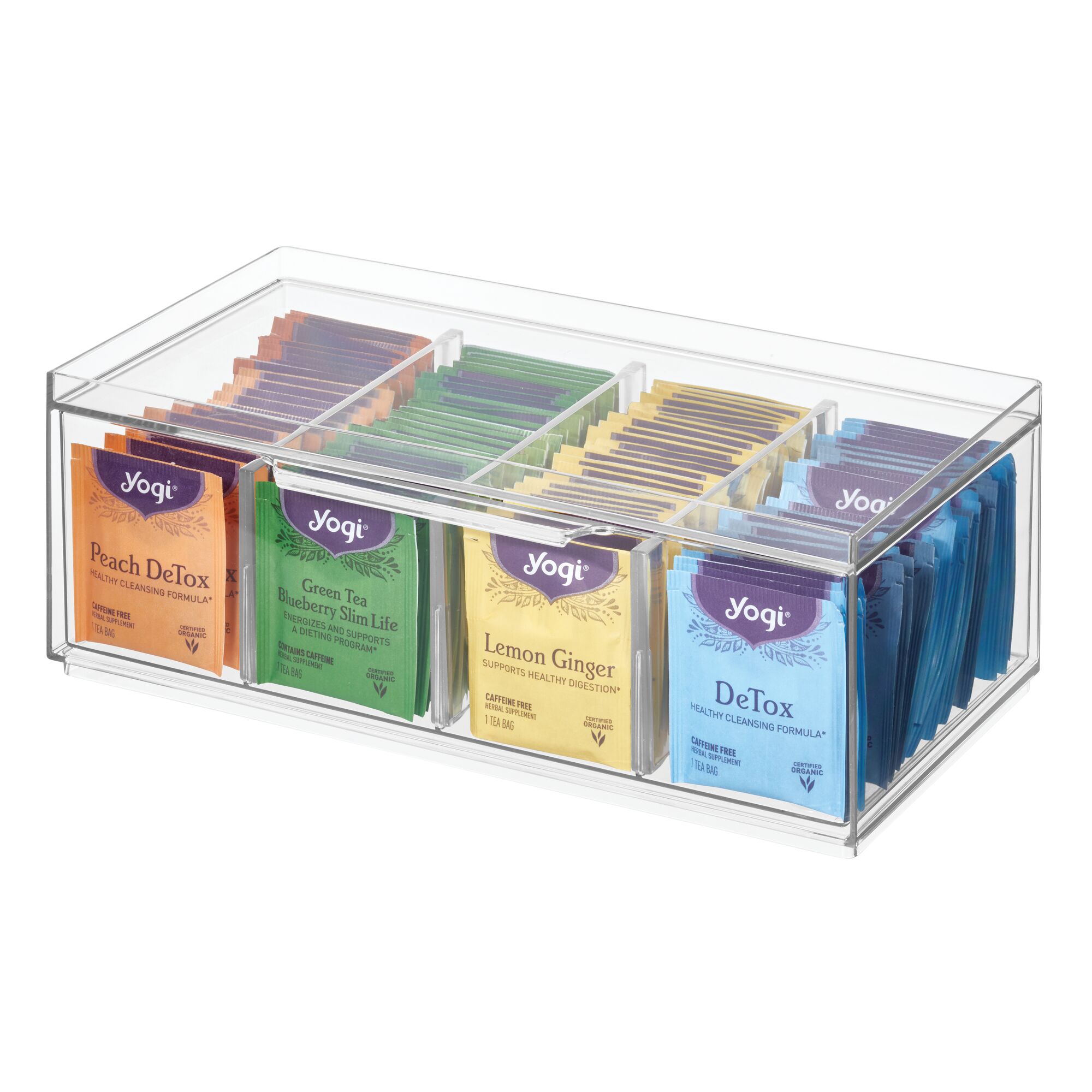 A Stackable Tea Organizer by iDesign, crafted from BPA-free recycled plastic, is filled with assorted Yogi tea packets. Sections display vibrant flavors like Peach DeTox, Green Tea Blueberry Slim Life, Lemon Ginger, and DeTox. Each colorful packet is neatly showcased.