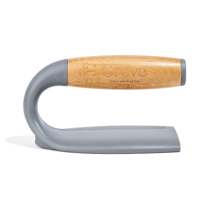 A gray and bamboo-handled cleaning tool with a curved design and flat bottom, branded with Grove Collaborative on the wooden handle.