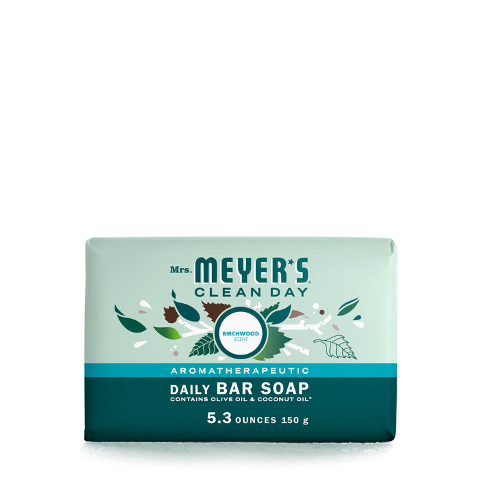 A light green bar of Mrs. Meyers Clean Day Aromatherapeutic Daily Bar Soap in Birchwood scent, featuring leaf illustrations and text highlighting olive oil and coconut oil ingredients, weighing 5.3 ounces (150 g).