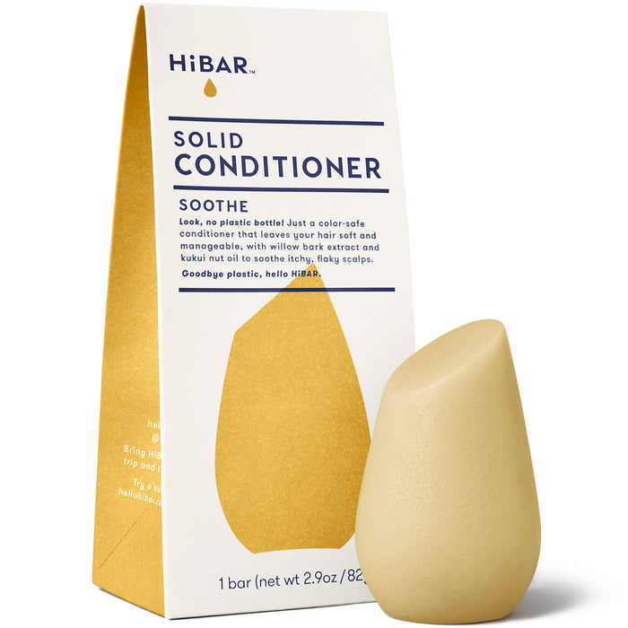A bar of HiBAR Solid Conditioner Soothe stands in front of its white and gold packaging, which highlights that the product is plastic-free and includes soothing ingredients like willow bark extract and kukui nut oil.