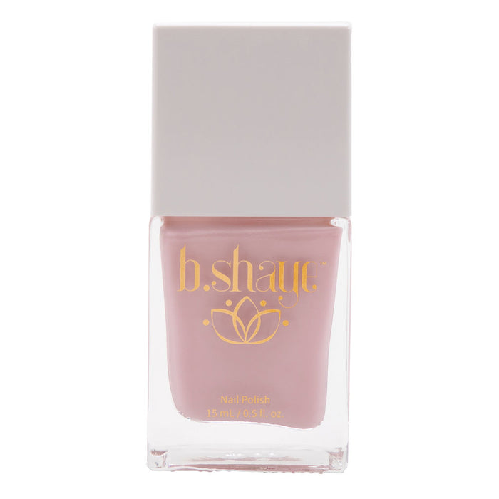 A square bottle of b.shaye nail polish in a soft pink shade, featuring gold lettering and a lotus flower design on the front. The label indicates the bottle contains 15 ml (0.5 fl oz) of nail polish.