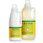 Two bottles from Mrs. Meyers Laundry Detergent & Fabric Softener Set are displayed. The Basil-scented detergent handles 64 loads, while the Honeysuckle fabric softener covers 32. Both feature yellow labels with green and white text.