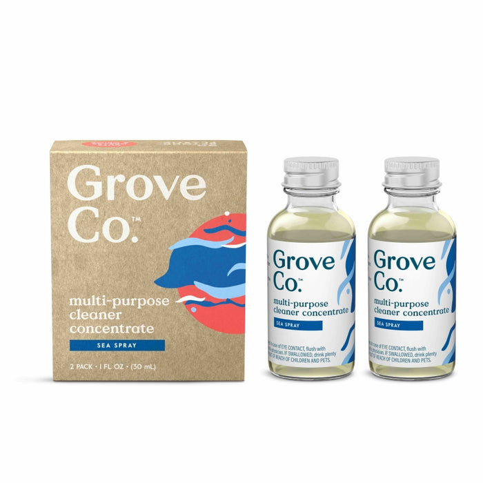 Two small glass bottles labeled Grove Co. multi-purpose cleaner concentrate, sea spray are next to a brown box with matching branding and a blue and red wave design. The box and bottles are arranged upright on a white background.
