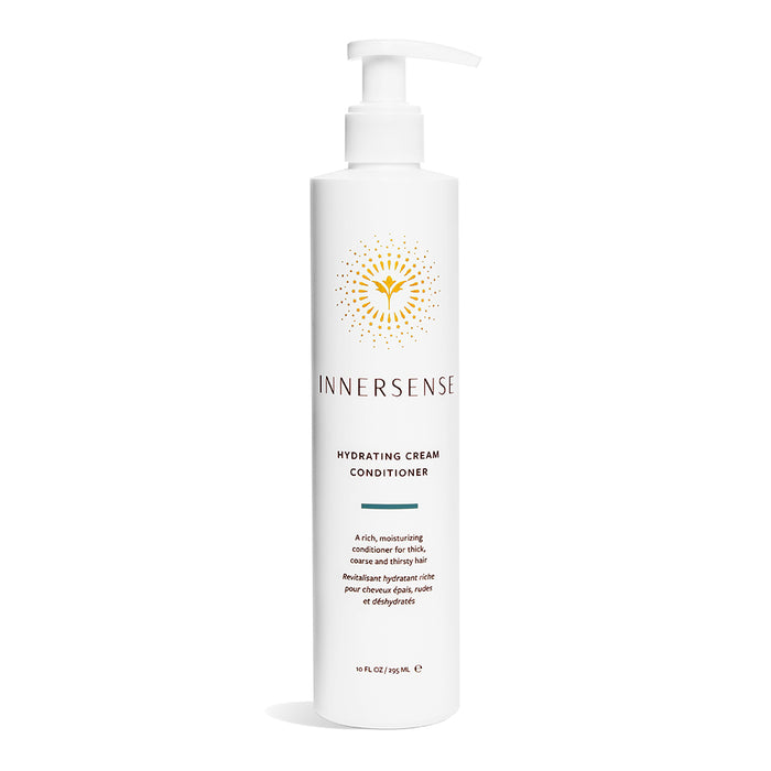 A white bottle of Innersense Organic Beautys Hydrating Cream Conditioner with a pump top stands elegantly on a white background, featuring a golden emblem on its label that highlights its organic ingredients.