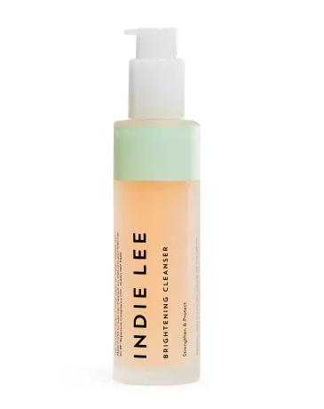 A clear bottle of INDIE LEE Brightening Cleanser with a white pump dispenser, featuring black text and a mint green accent near the top.
