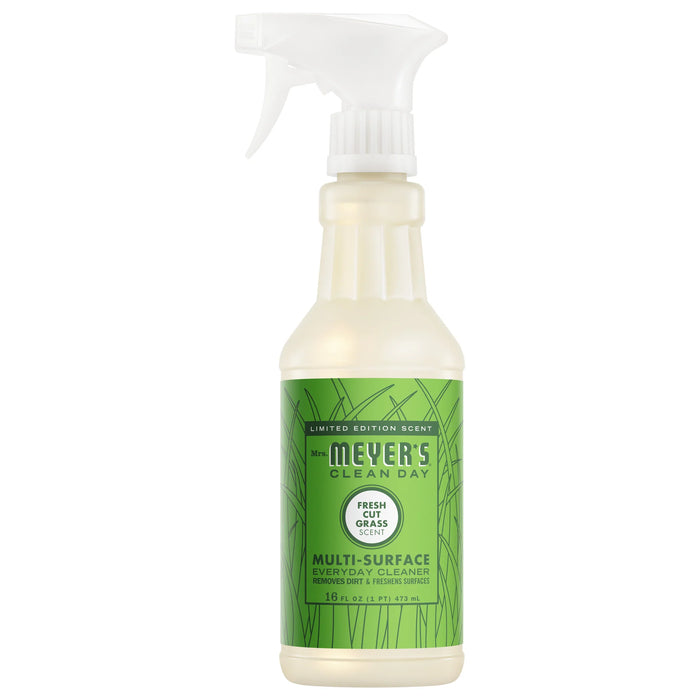 A bottle of Mrs. Meyer's Multi-Surface Cleaner in Fresh Cut Grass scent features a green label with grass designs and a white spray nozzle, bringing a fresh essential oil fragrance to your space with every spray.