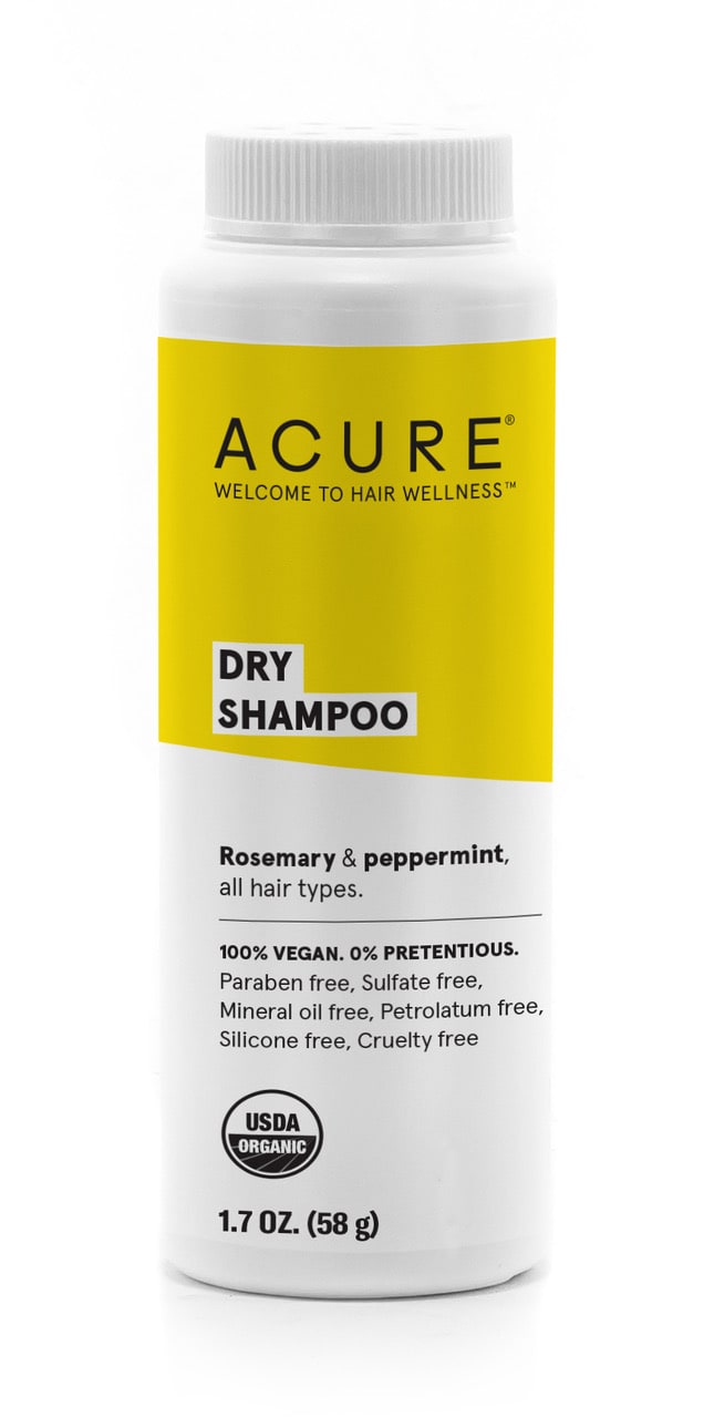 A white bottle of Acure Dry Shampoo with a yellow label stating it is rosemary & peppermint scented, suitable for all hair types, vegan, and USDA organic, with a net weight of 1.7 oz (58 g).