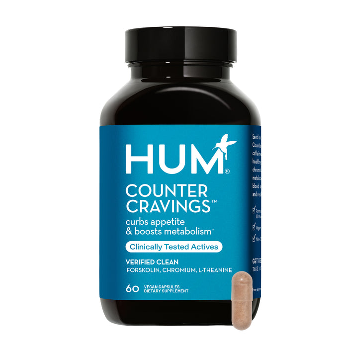 A bottle of HUM Counter Cravings dietary supplement with a blue label that promotes curbing appetite and boosting metabolism; a single capsule is placed in front of the bottle.