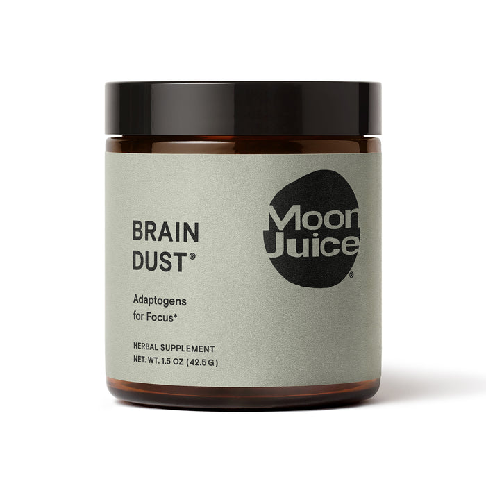 A brown jar labeled Brain Dust by Moon Juice, described as herbal supplements with adaptogens for focus. The label is light gray with black text and a black Moon Juice logo.