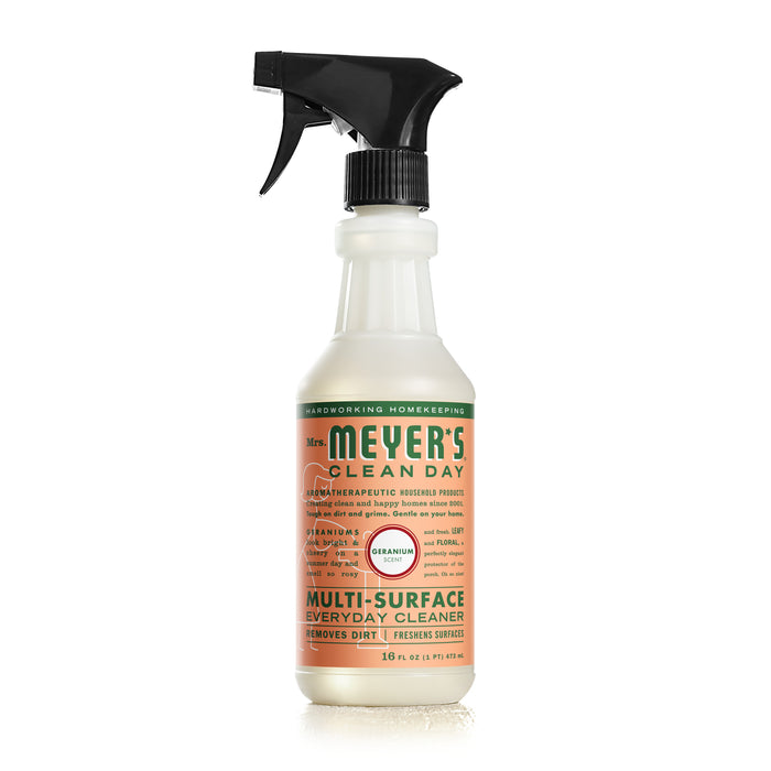 A bottle of Mrs. Meyer’s Clean Day Multi-Surface Everyday Cleaner in Geranium scent, with a white spray nozzle and a green, orange, and white label, standing upright on a white background.
