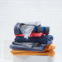 A stack of neatly folded cleaning cloths in various colors, including gray, pink, navy blue, and orange, set against a white tiled background.